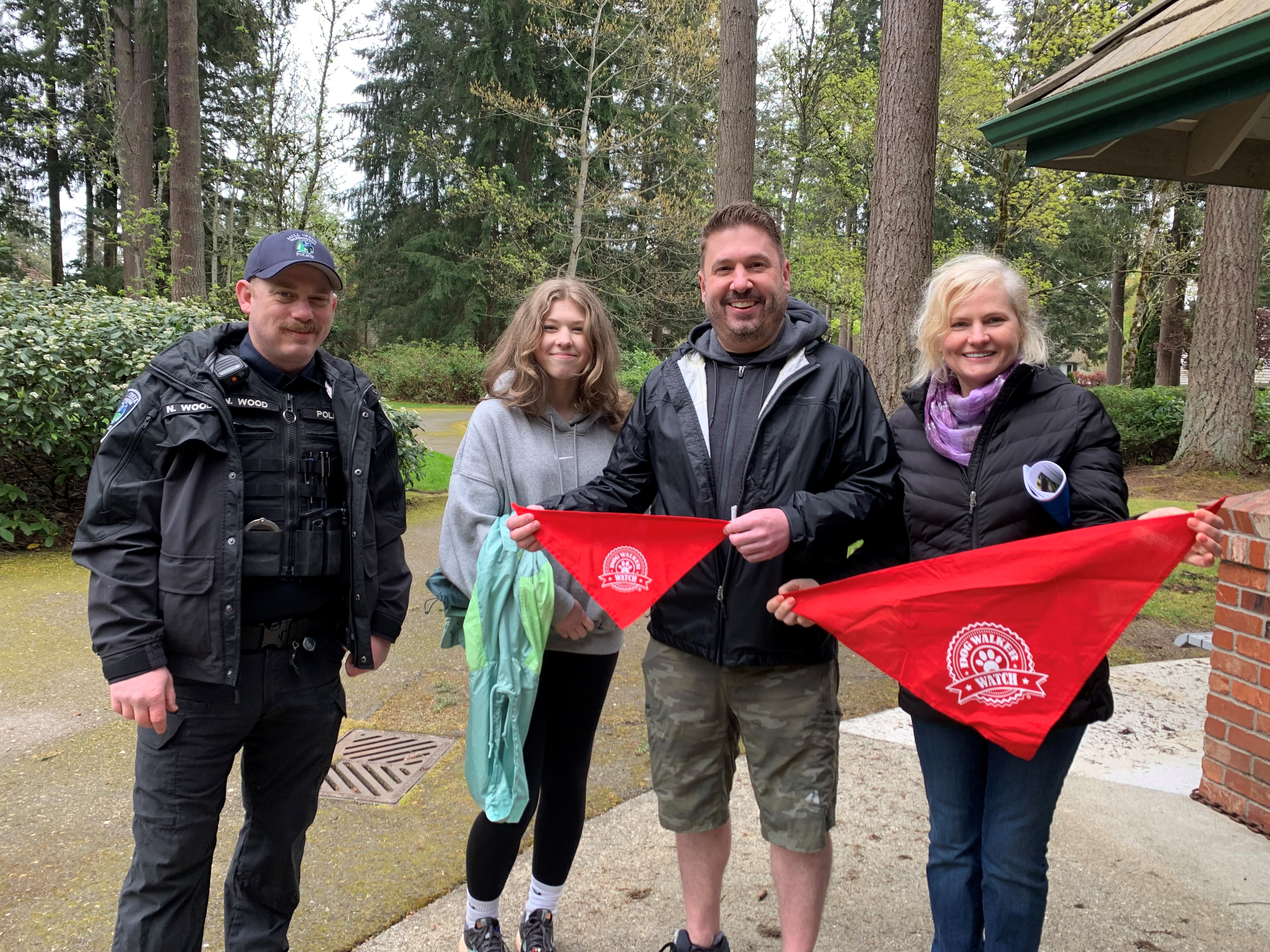 Group of Dog Walker Watch attendees holding up dog bandanas in Heron Park.
