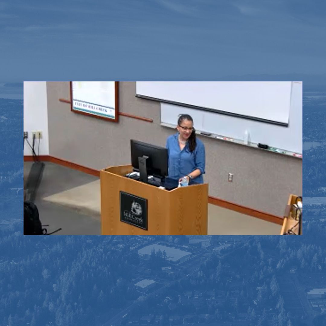 Representative April Berg stands at the podium in Mill Creek City Council Chambers to present. 